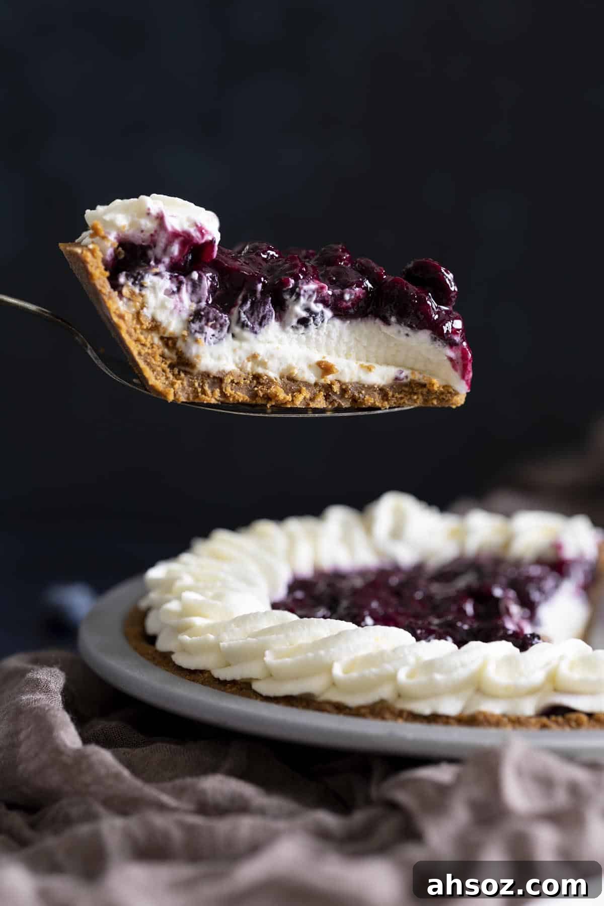A slice of blueberry cream cheese pie is lifted up with a pie server.