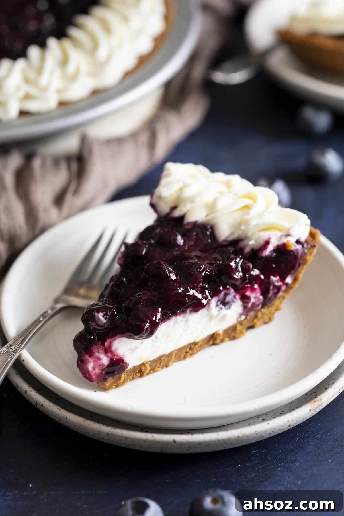 A slice of blueberry cream cheese pie on a white plate.