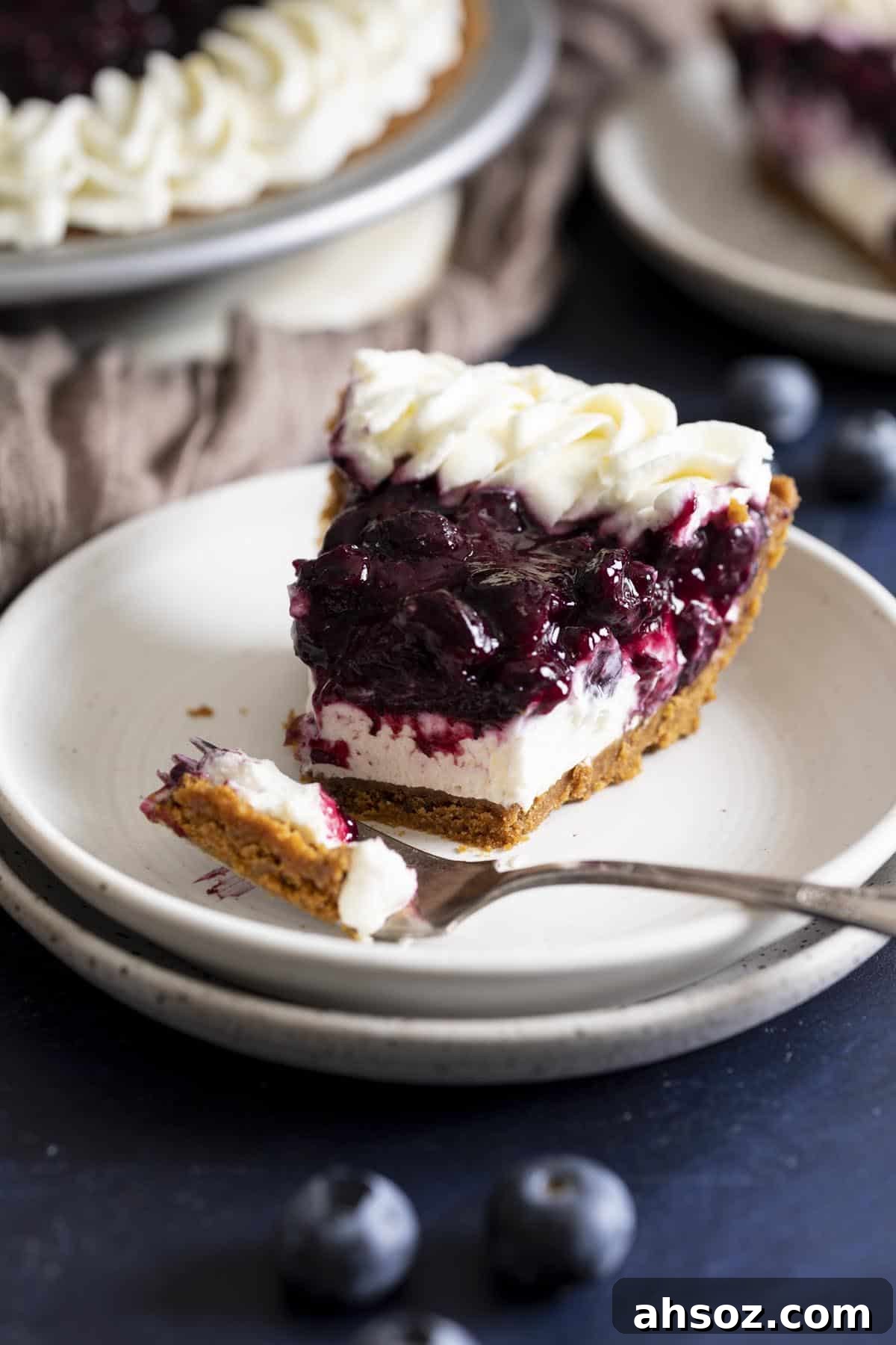A slice of no bake blueberry cream cheese pie with a bite taken out.