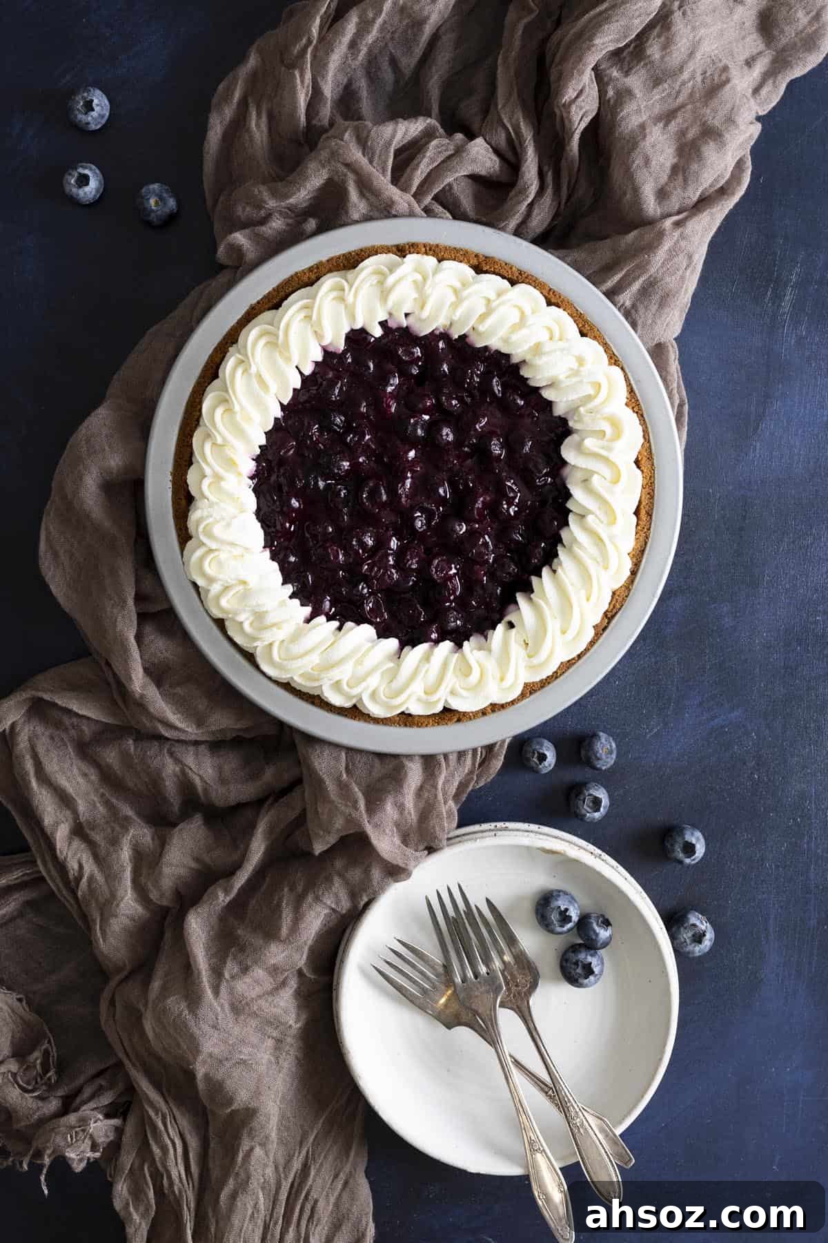 A no bake blueberry pie with Graham cracker crust next to a stack of white plates.
