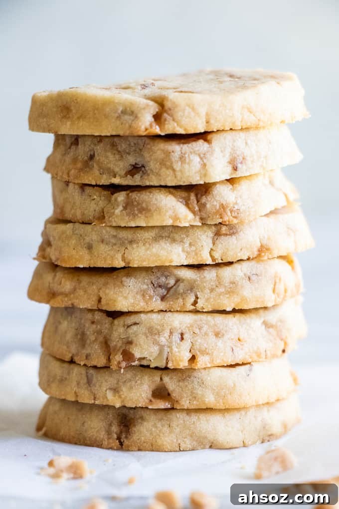 Large stack of butter pecan shortbread cookies, loaded with bits of chopped pecans and toffee bits.