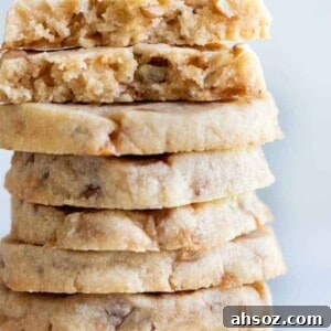 A stack of butter pecan shortbread cookies with bits of pecans and toffee bits around.