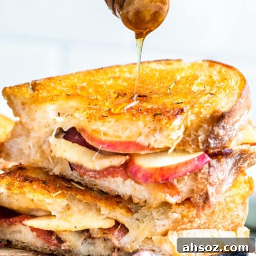 Hand drizzling honey over top of stack of sandwiches.