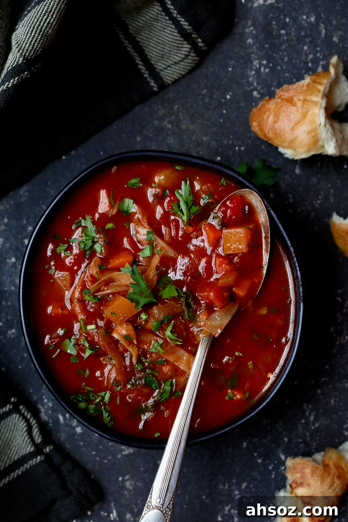 Rustic Cabbage and Root Vegetable Soup in black bowl garnished with parsley.