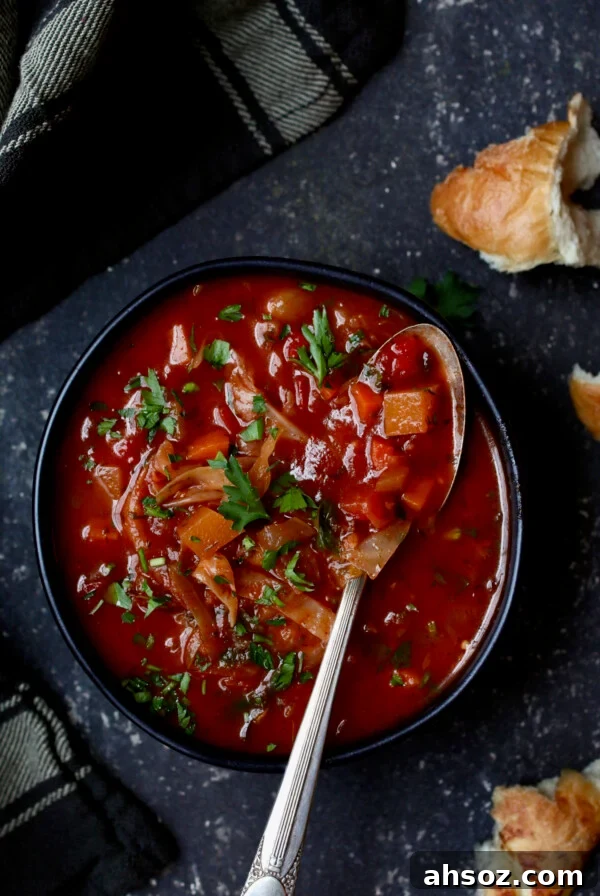 Rustic Cabbage and Root Vegetable Soup in black bowl garnished with parsley.
