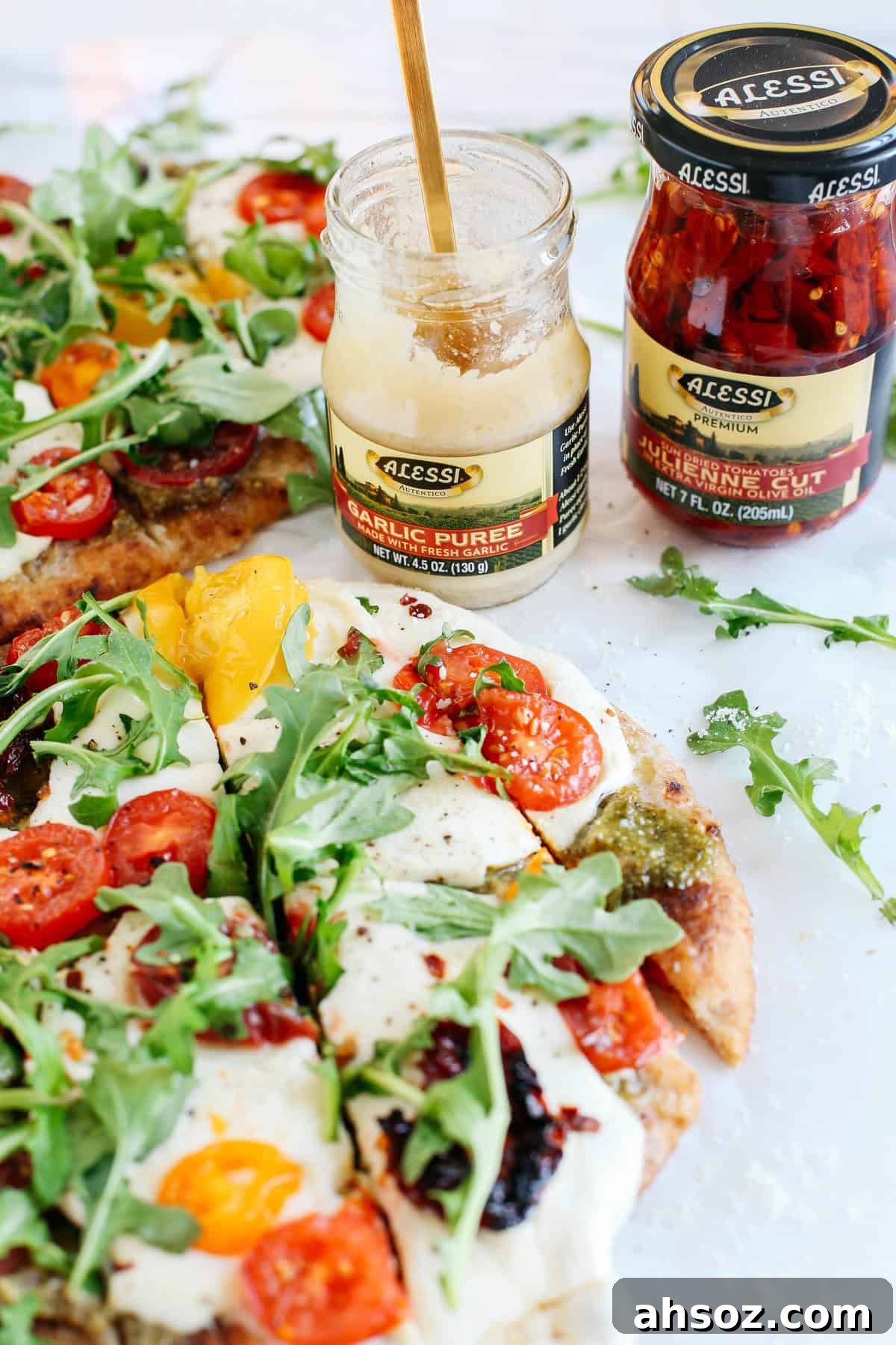 Garlicky pesto flatbread pizza topped with tomatoes, mozzarella and arugula