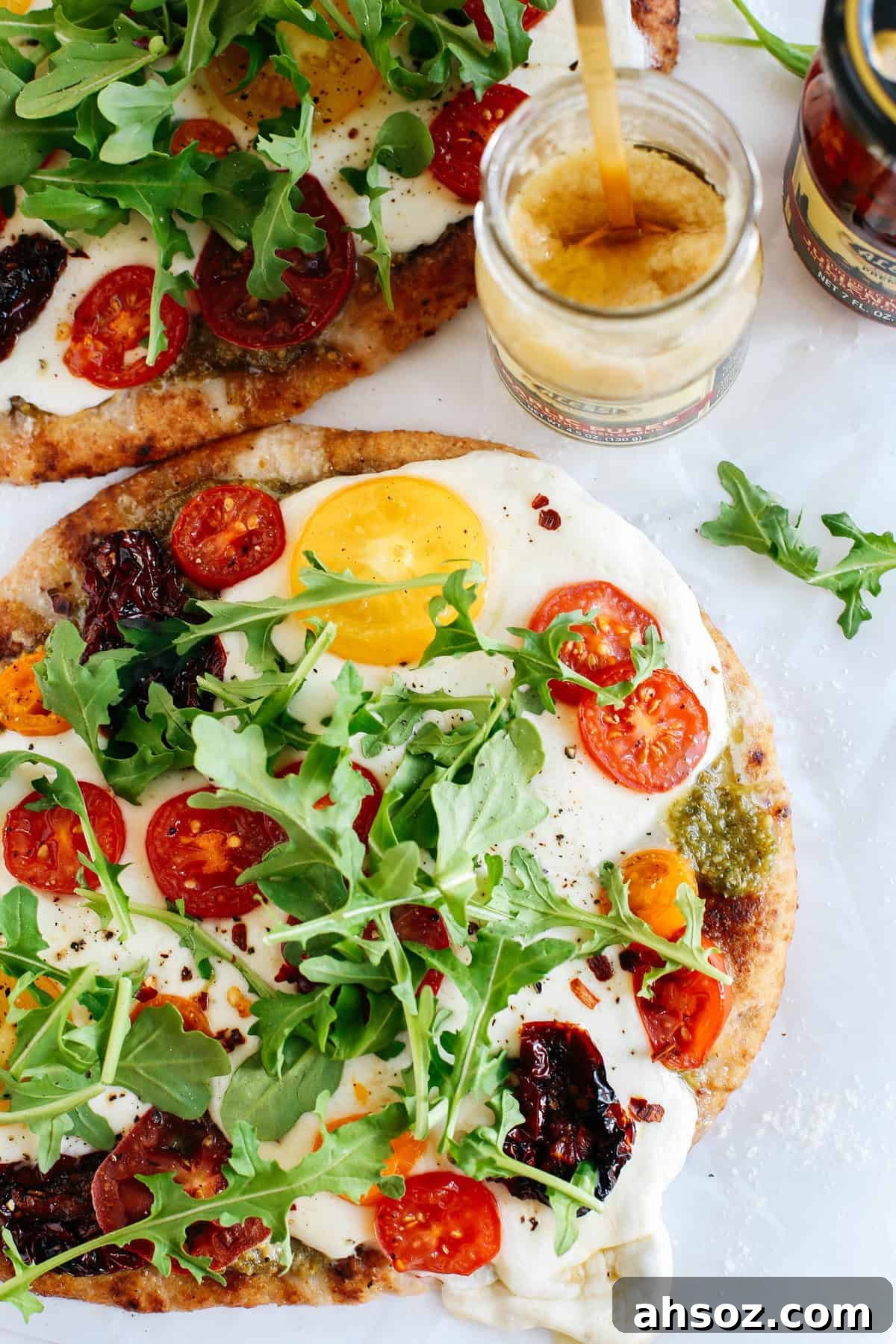 Flatbread pizzas brushed with garlic puree and topped with pesto and tomatoes