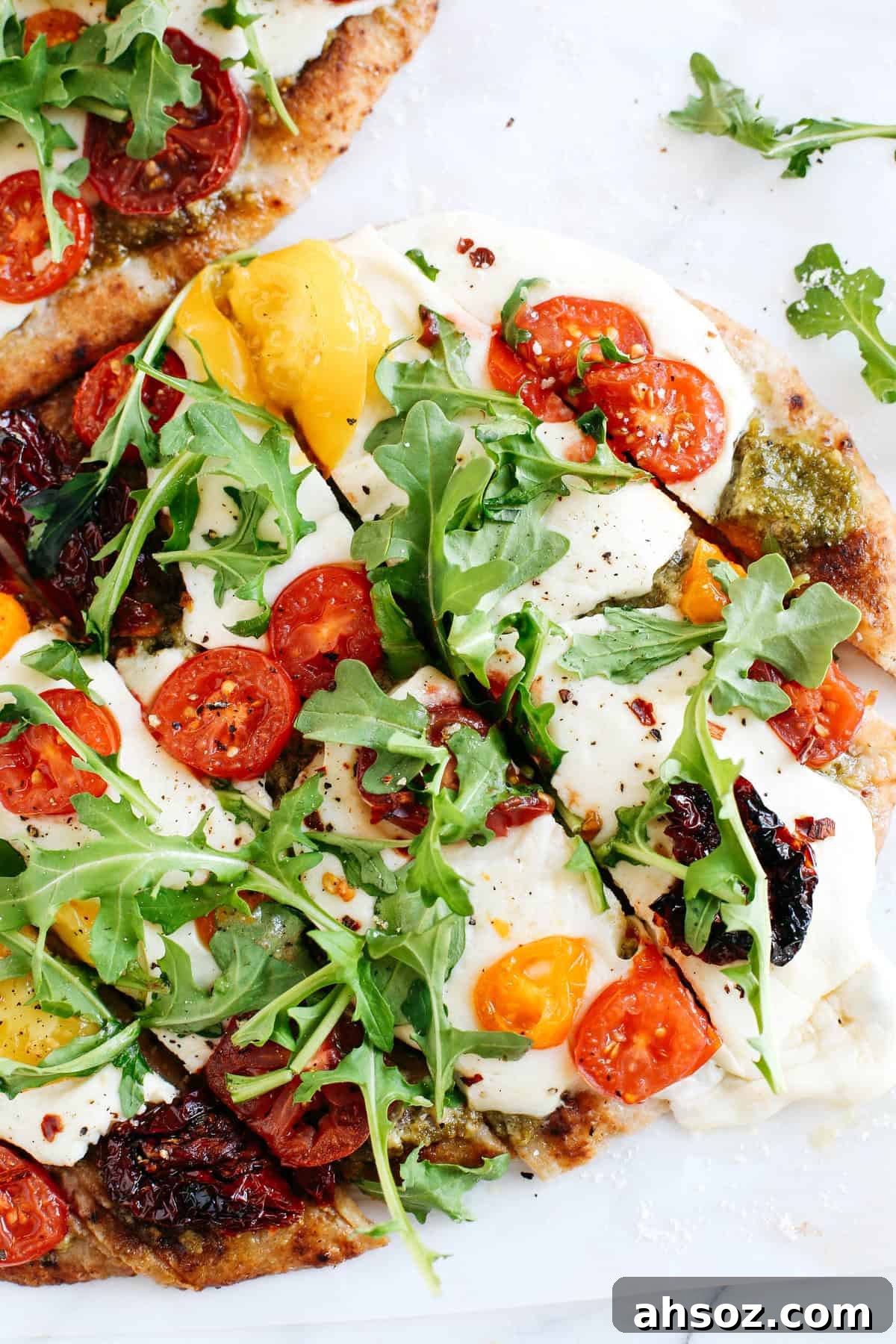 Baked pesto flatbread pizza with fresh tomatoes and melted mozzarella