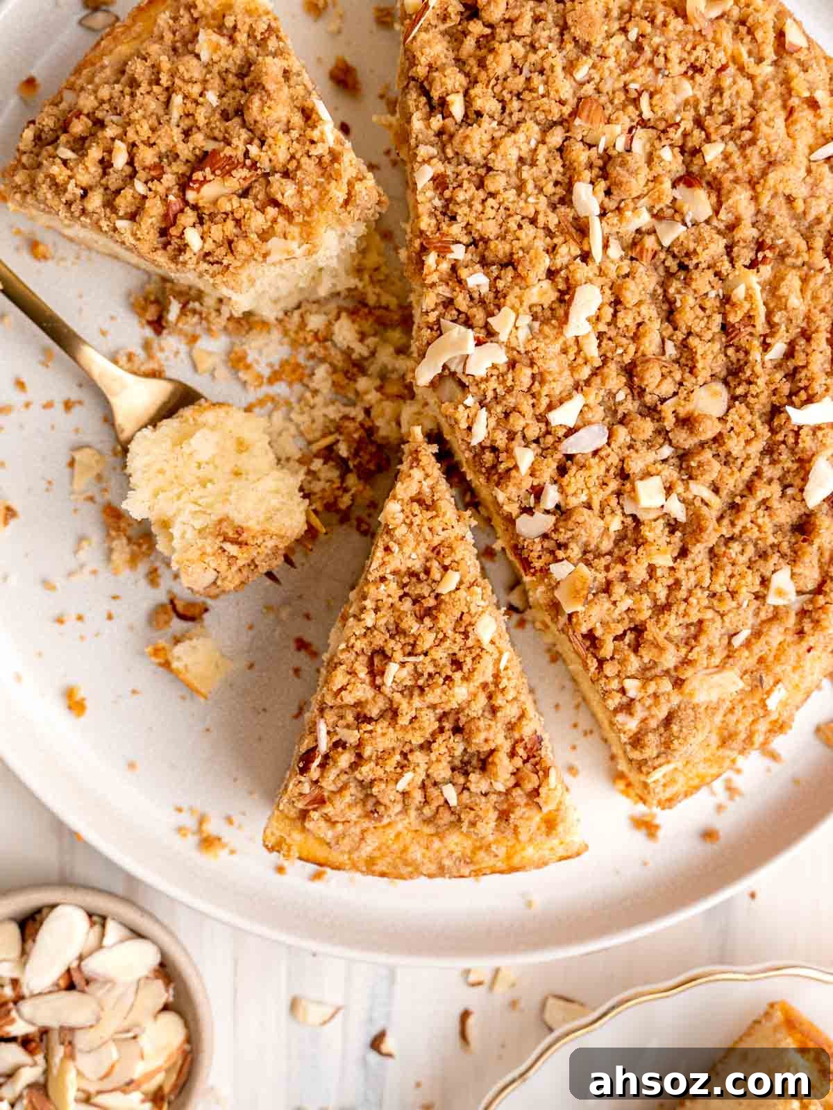An almond coffee cake cut into slices on a plate.