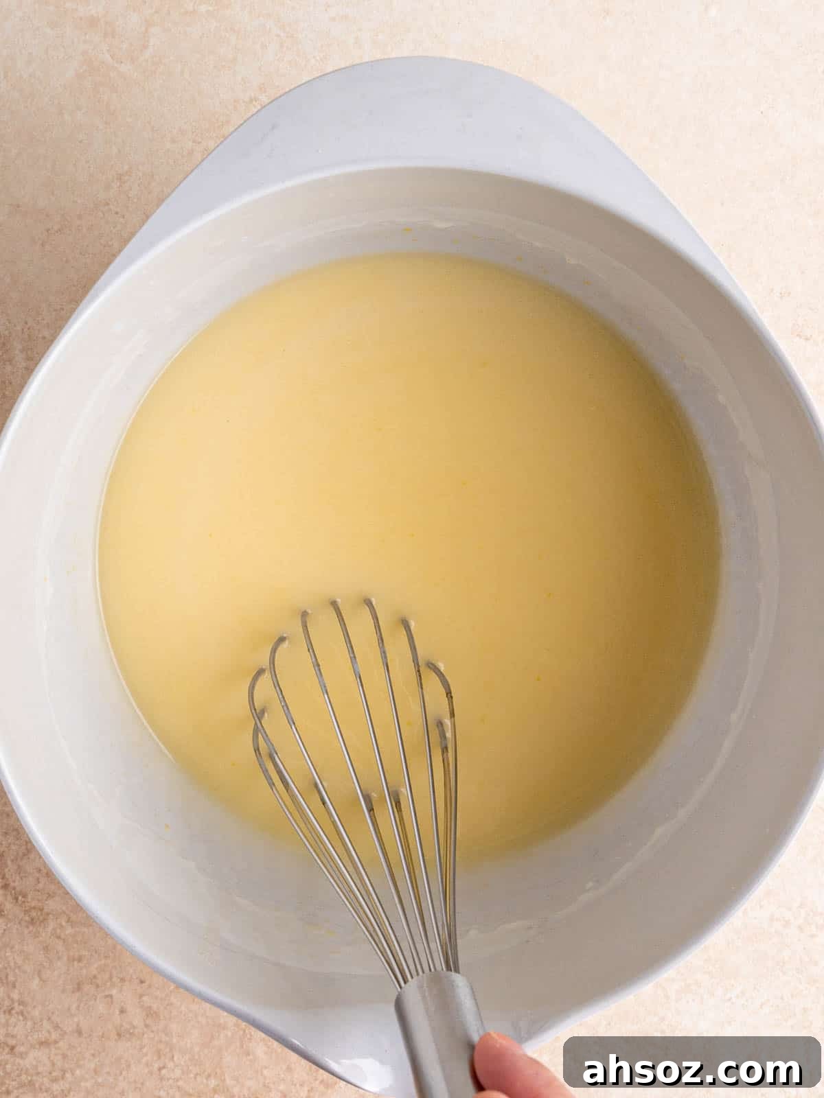 Whisking wet cake ingredients in a bowl.