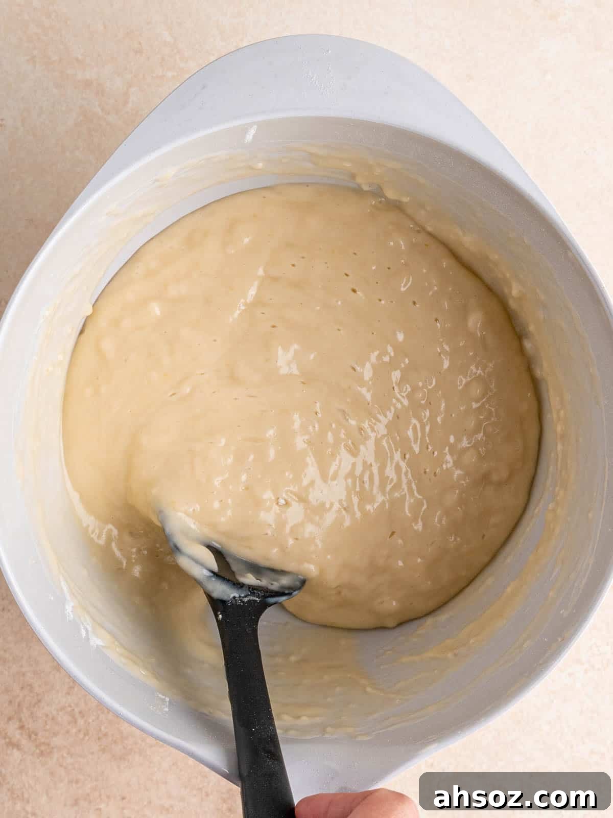 Folding almond flavored cake batter in a bowl with a spatula.