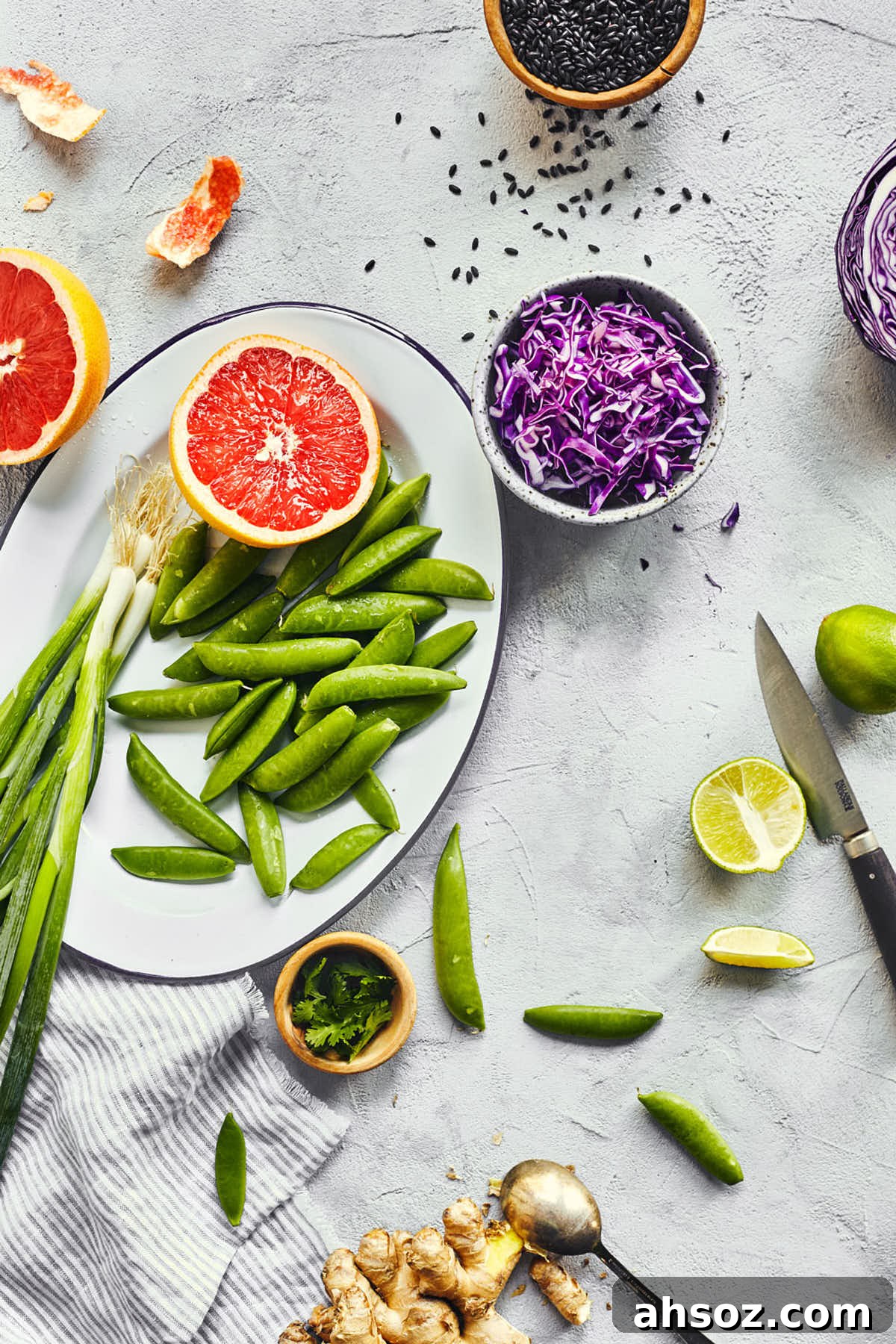 Asian black rice salad ingredients like scallions, grapefruit, purple cabbage, snap peas and limes on the counter