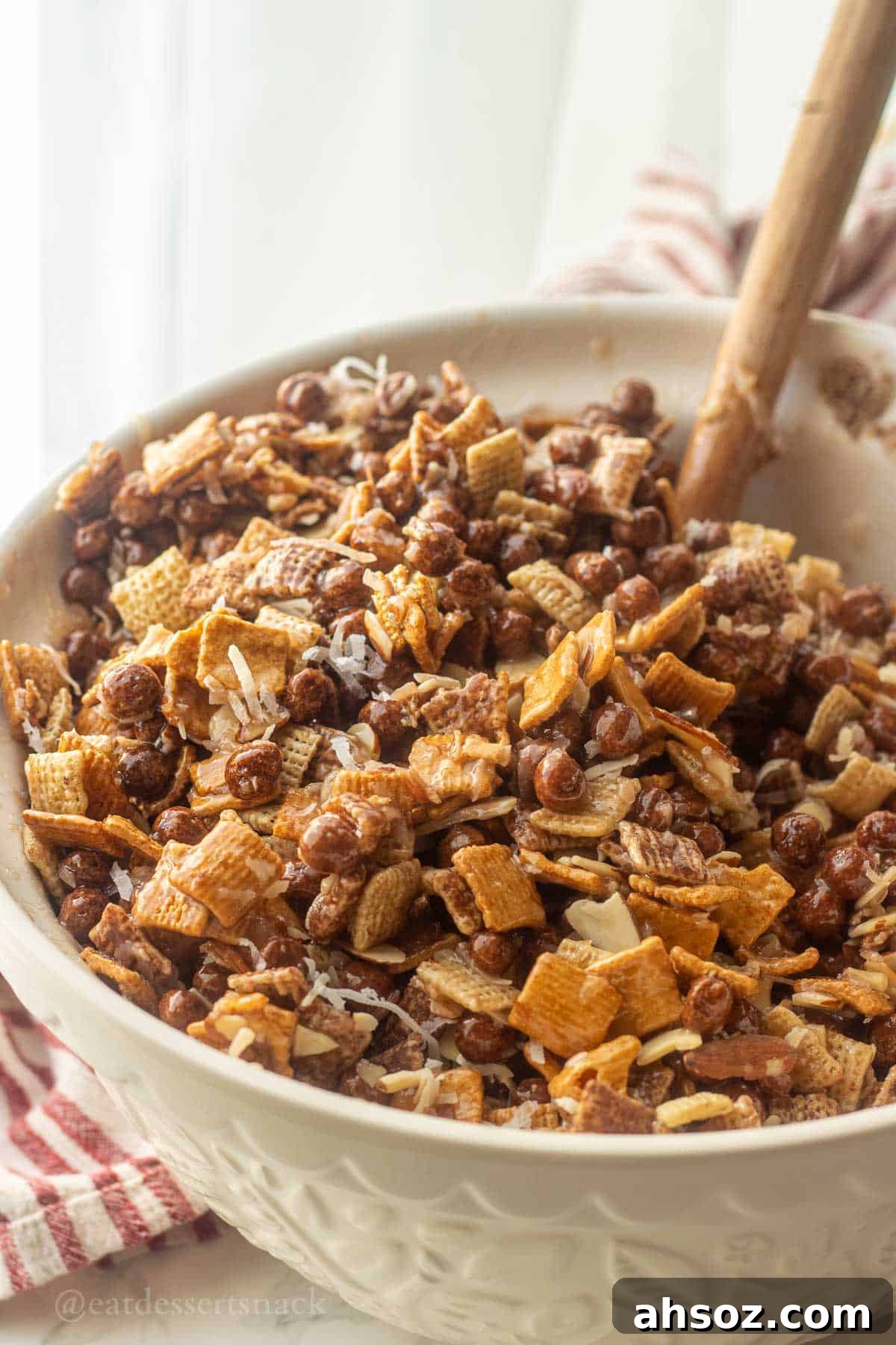 Chocolate Chex mix in bowl with wooden spatula.