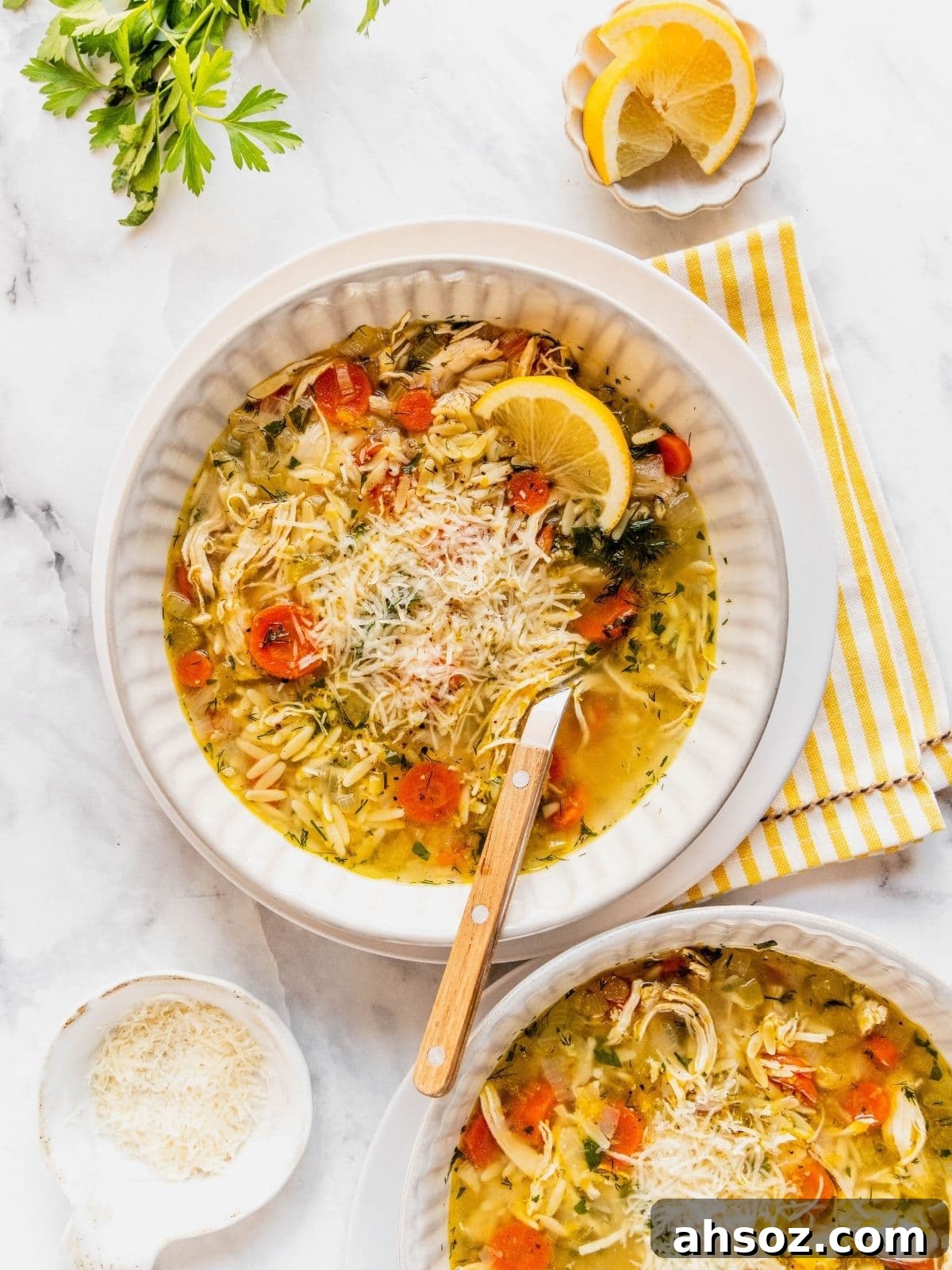 Lemon chicken orzo soup garnished with herbs and parmesan cheese in a bowl.