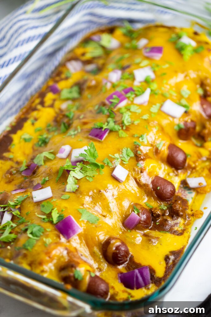 Chili cheese dog casserole in a glass 9-inch by 13-inch casserole dish topped with cilantro and red onions