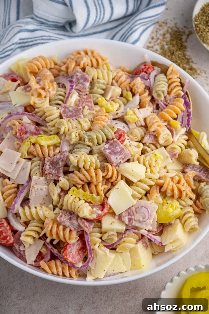A white bowl filled with Italian sub grinder pasta salad filled with deli meats, cheese, and vegetables.