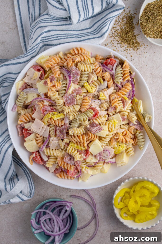 Overhead view of a white bowl with colorful Italian grinder pasta salad filled with deli meats, cheeses, and veggies.