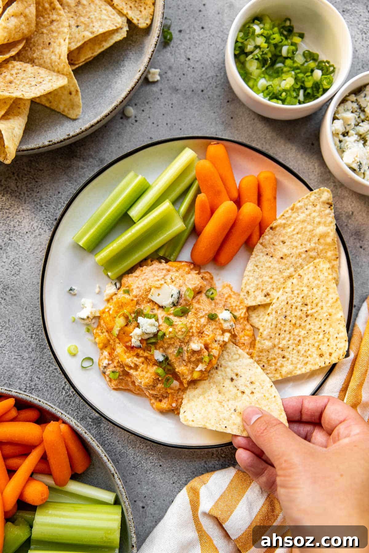 buffalo chicken dip on a plate with chips, celery and baby carrots. 