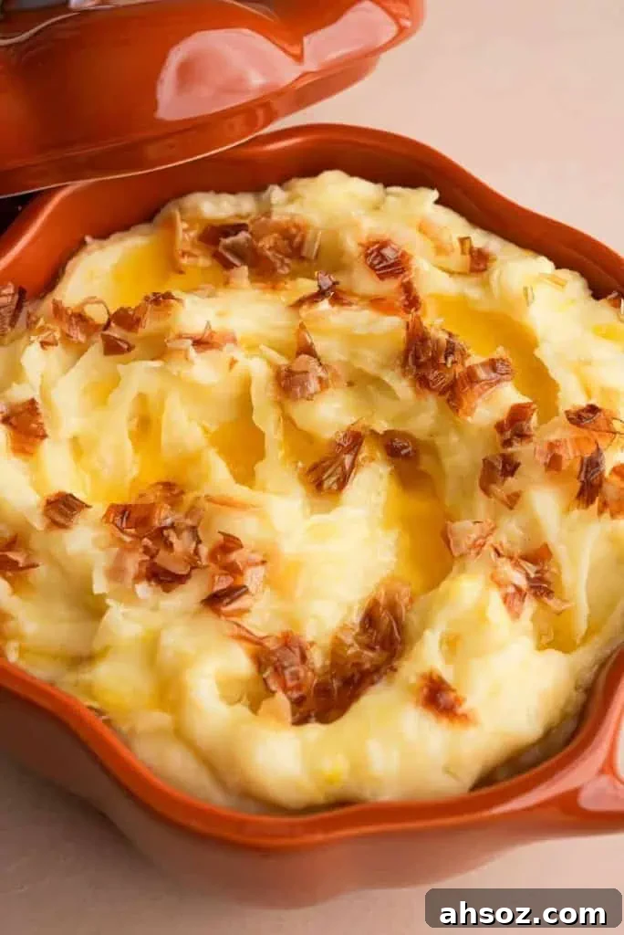 A ceramic dish of mashed potatoes topped with roasted leeks and melted butter, ready to serve.