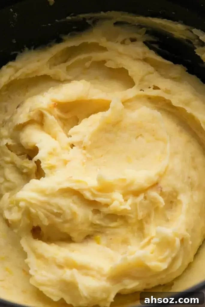 A close-up of smooth, creamy mashed potatoes blended with bits of roasted leeks.