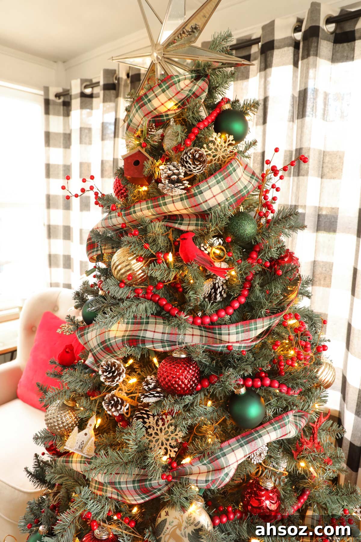 A traditional red and green Christmas tree decorated with plaid ribbon, red garland, and ornaments.