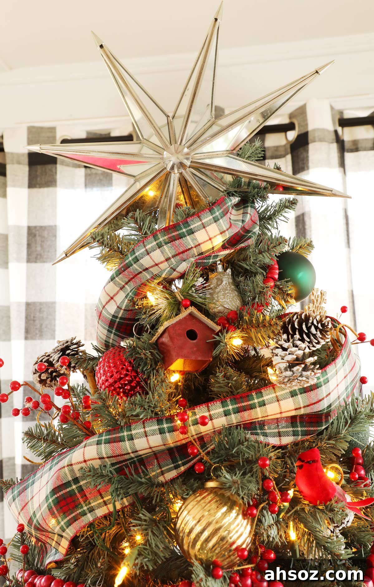 A mirrored star Christmas tree topper on a red and green Christmas tree.