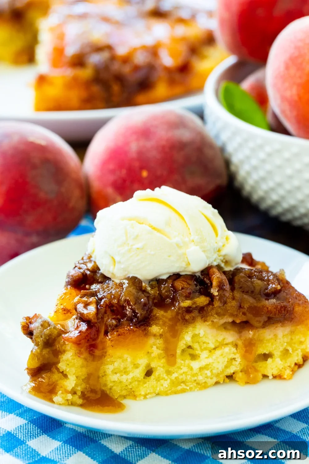 Peach Praline Upside Down Cake slice on a plate surrounded by fresh peaches.