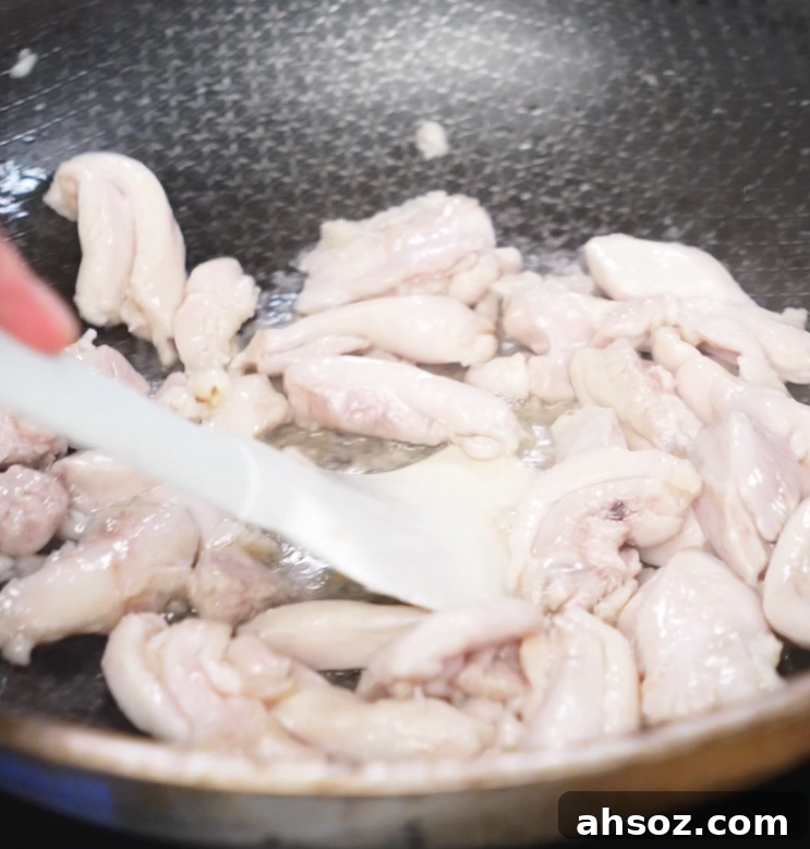 Marinated chicken thighs cook in a hot pan until lightly browned and tender, forming the protein base of the dish.