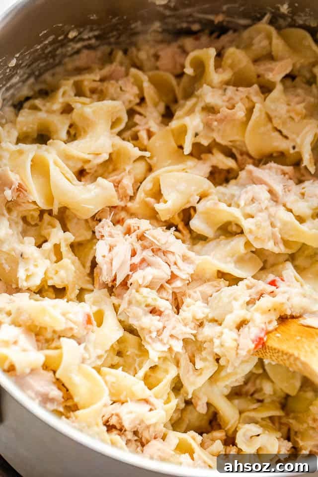 a pot filled with cooked egg noodles mixed with canned tuna