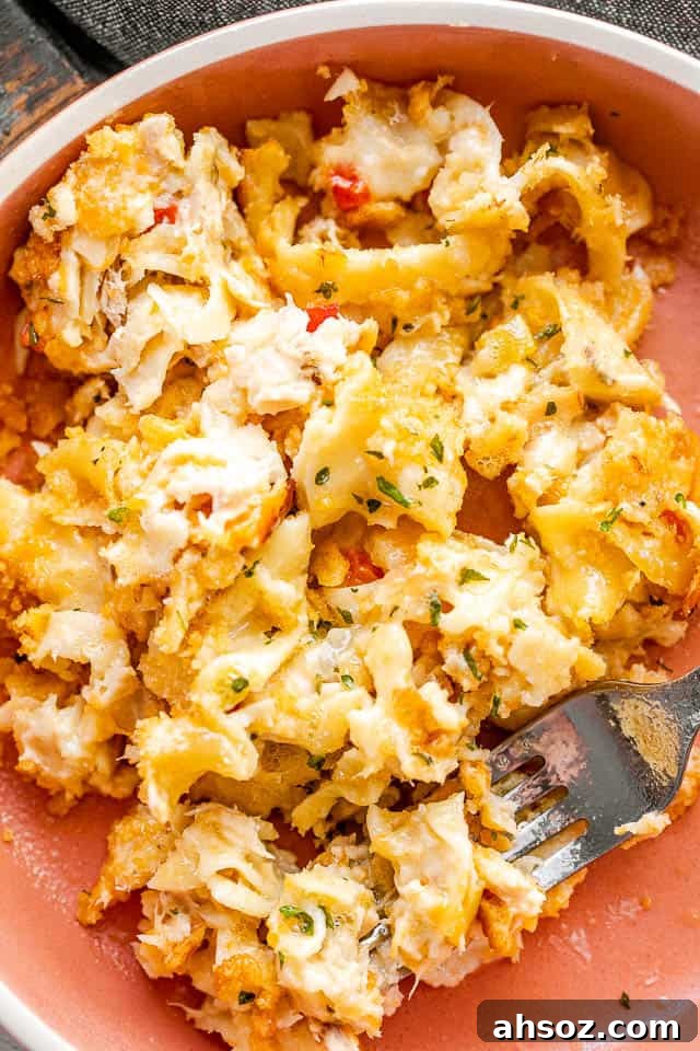 serving tuna noodle casserole in an orange bowl with a silver fork