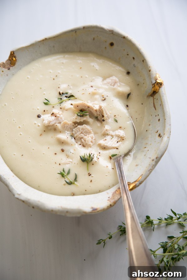 Bowl of gluten-free cream of chicken soup with thyme sprigs and spoon