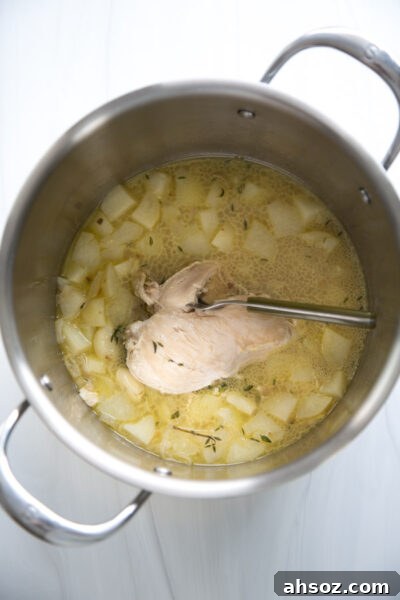 potatoes aromatics and chicken simmering in broth