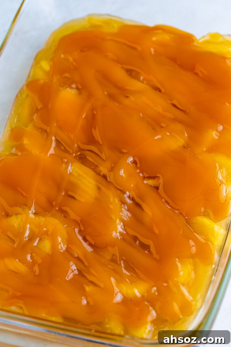apple pie filling in a baking dish with caramel sauce spread over top