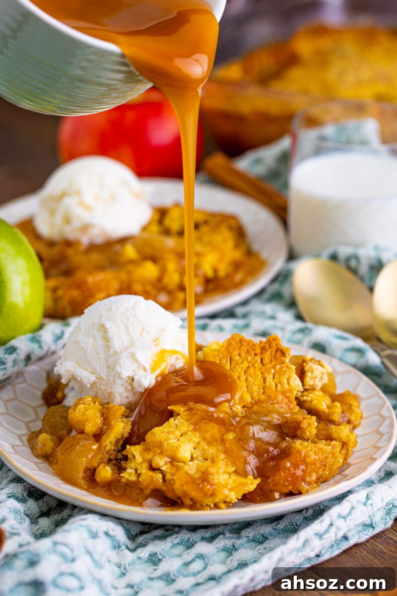 caramel sauce being poured over a portion of caramel apple dump cake on a plate with vanilla ice cream