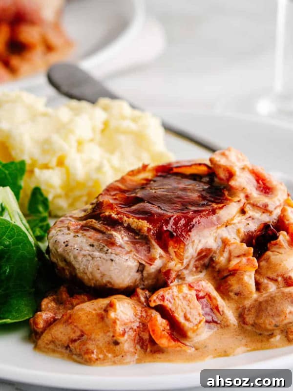 Pork Saltimbocca served on a white plate with greens and mashed potatoes.