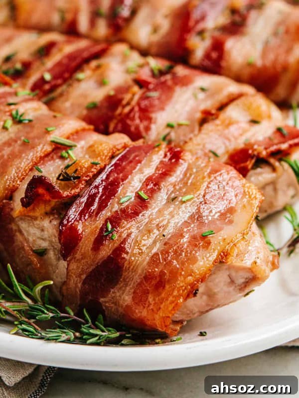 Bacon Wrapped Pork Chops served on a white oval platter with rosemary sprigs.