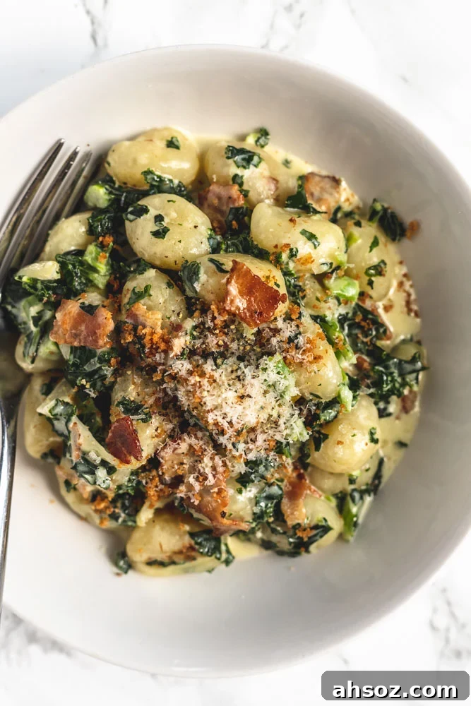 A bowl of creamy kale gnocchi with bacon and onions.