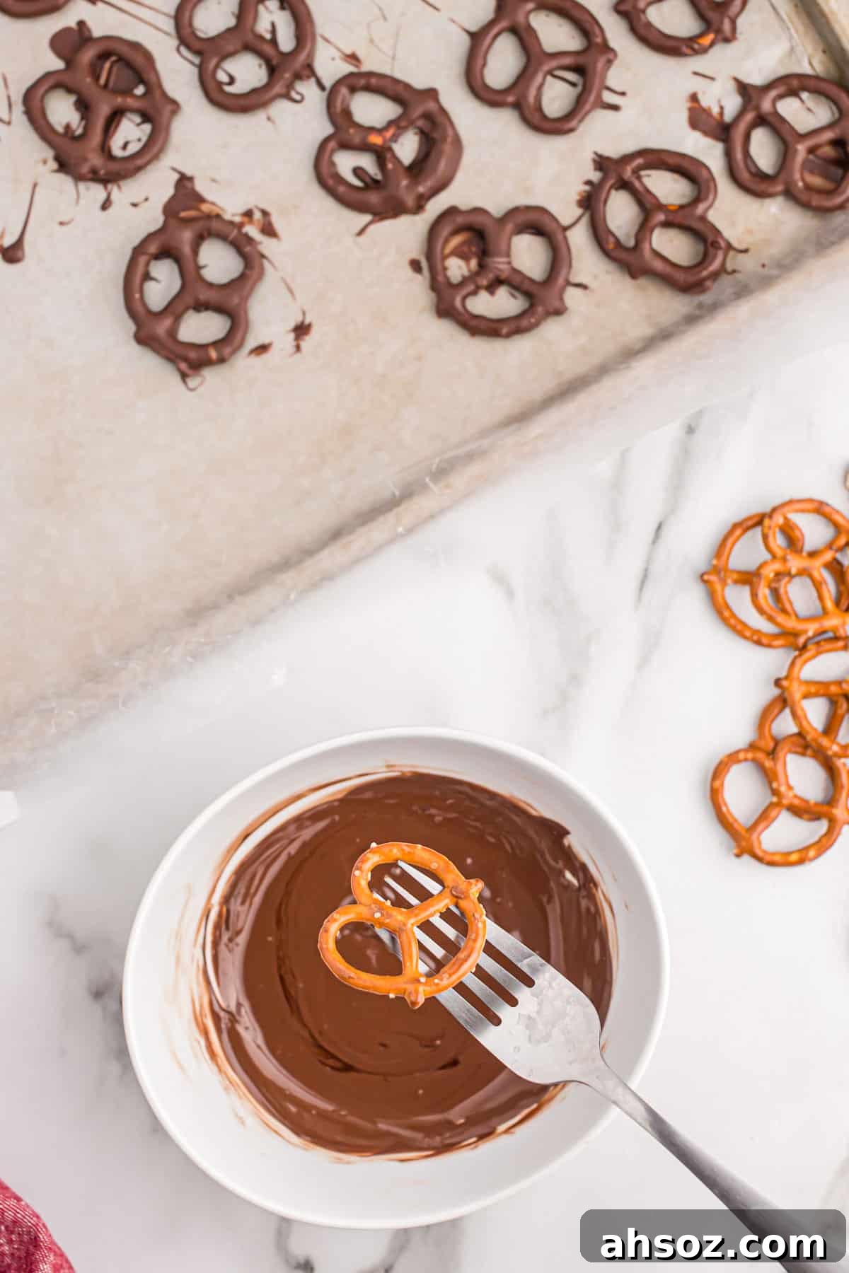 holding a pretzel over a small bowl of melted dark chocolate