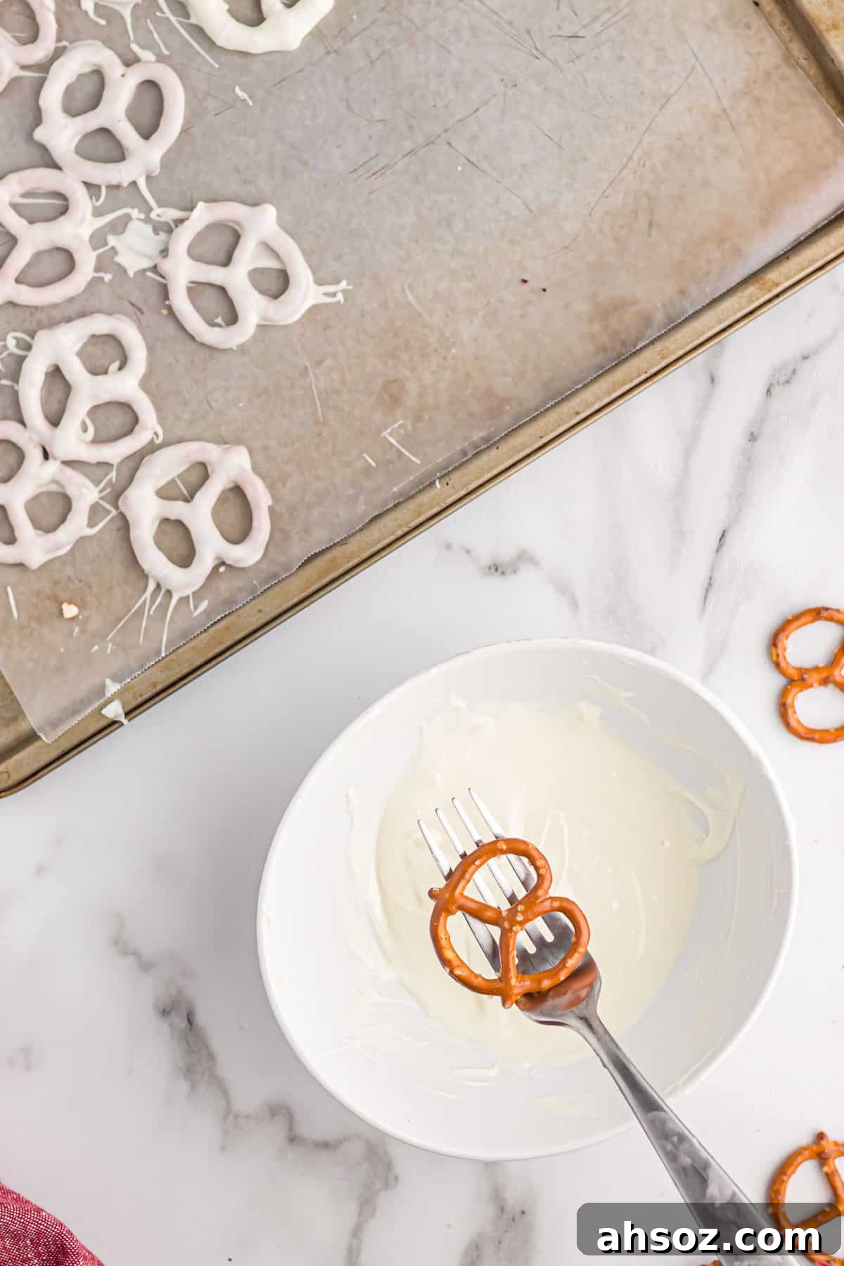 holding a pretzel over a small bowl of melted white chocolate