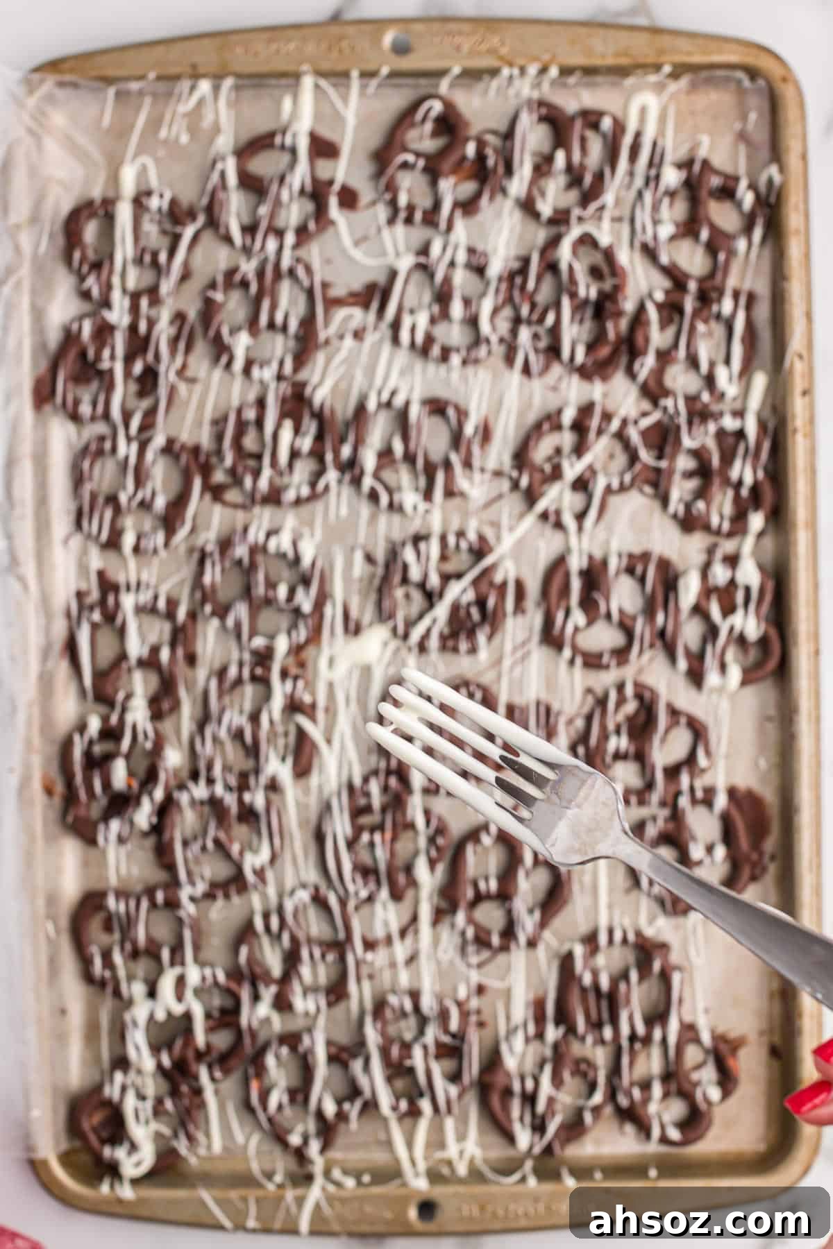 drizzling white chocolate over the dark chocolate pretzels