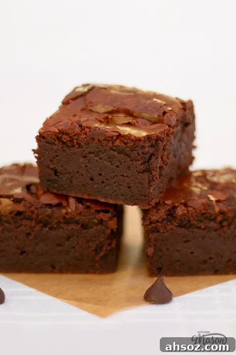 Chocolate brownies in a tower on a square of baking paper.