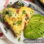 This is a square picture of a slice of frittata with avocado on the side.