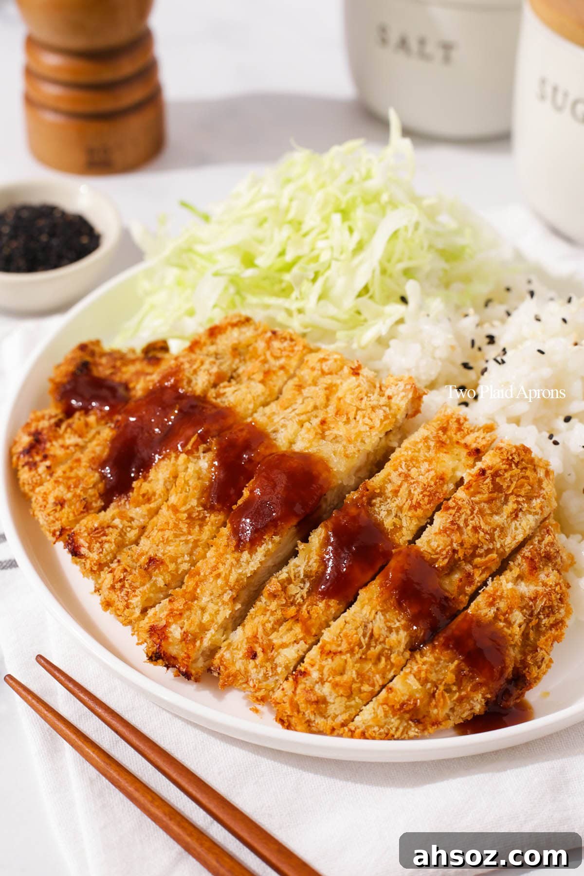 Sliced air fryer chicken katsu with rice and cabbage.