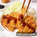 Picking up a piece of air fried chicken katsu with chopsticks.