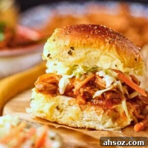 Barbecue chicken sliders sitting on a wooden serving platter.