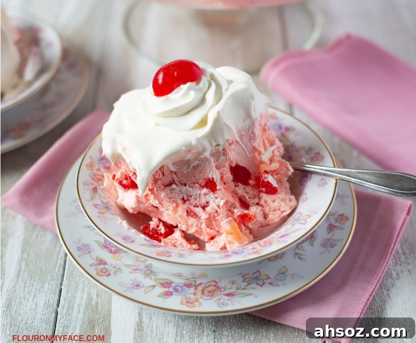 Pink Salad recipe made with maraschino cherries topped with Cool Whip and served on a vintage floral dessert dish.