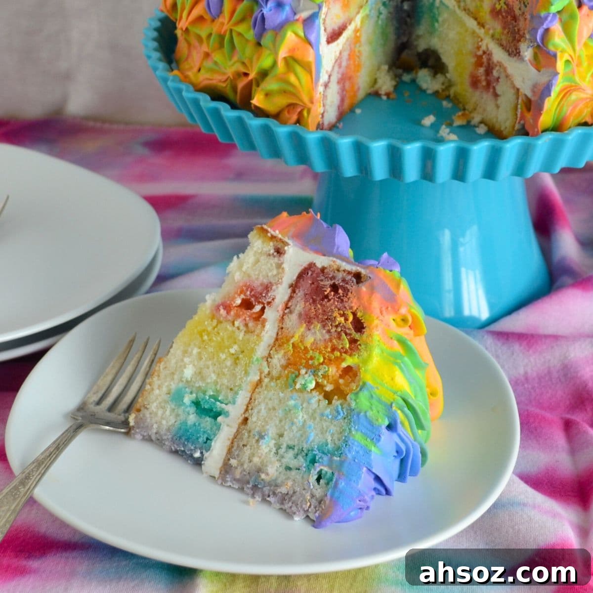 A thick slice of rainbow poke cake served on a plate.