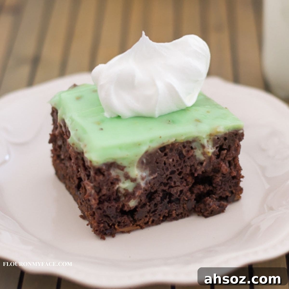 Pistachio Poke Cake on a plate topped with whipped cream.