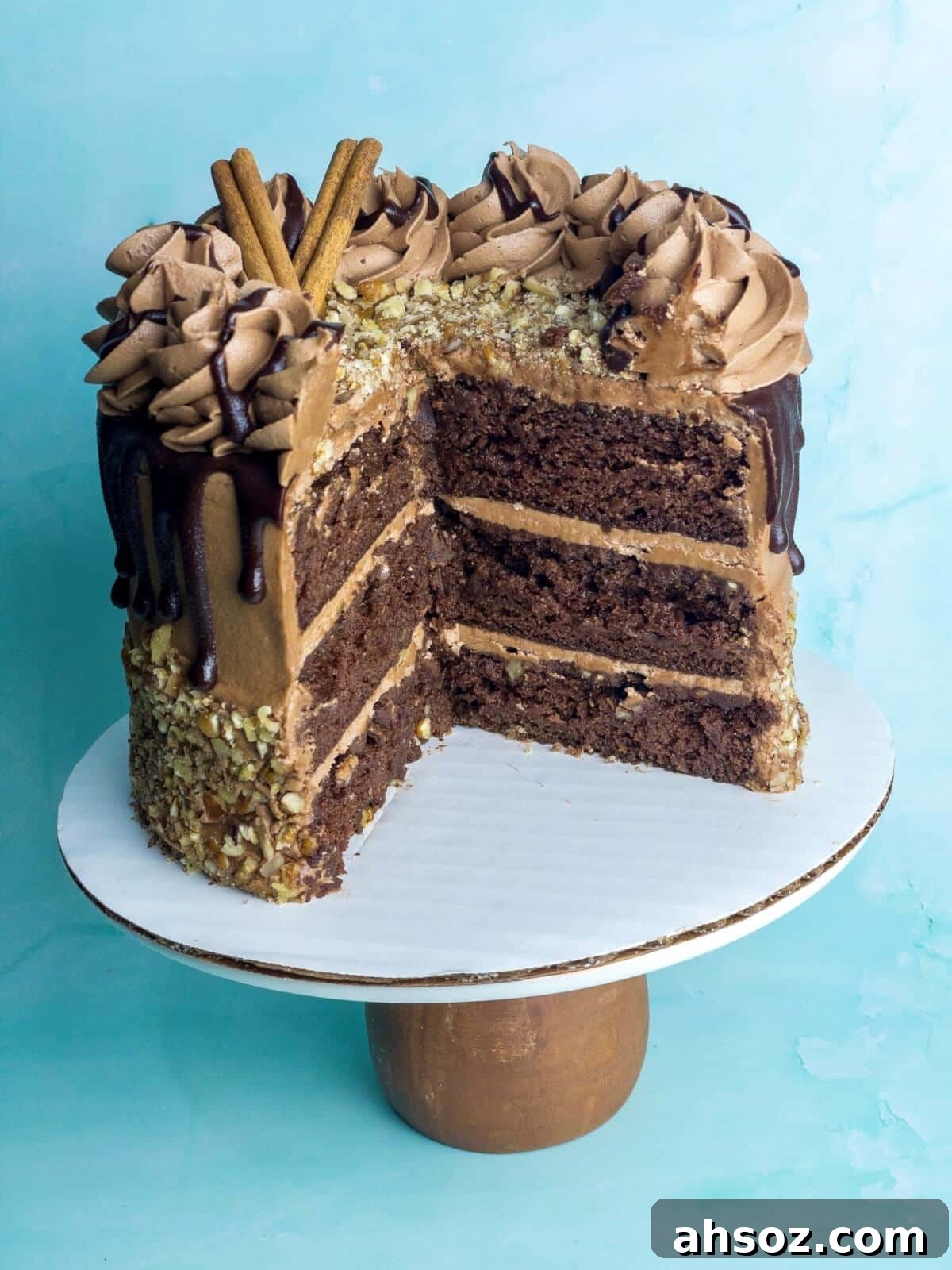 A chocolate cinnamon layer cake on a cake stand with several slices missing