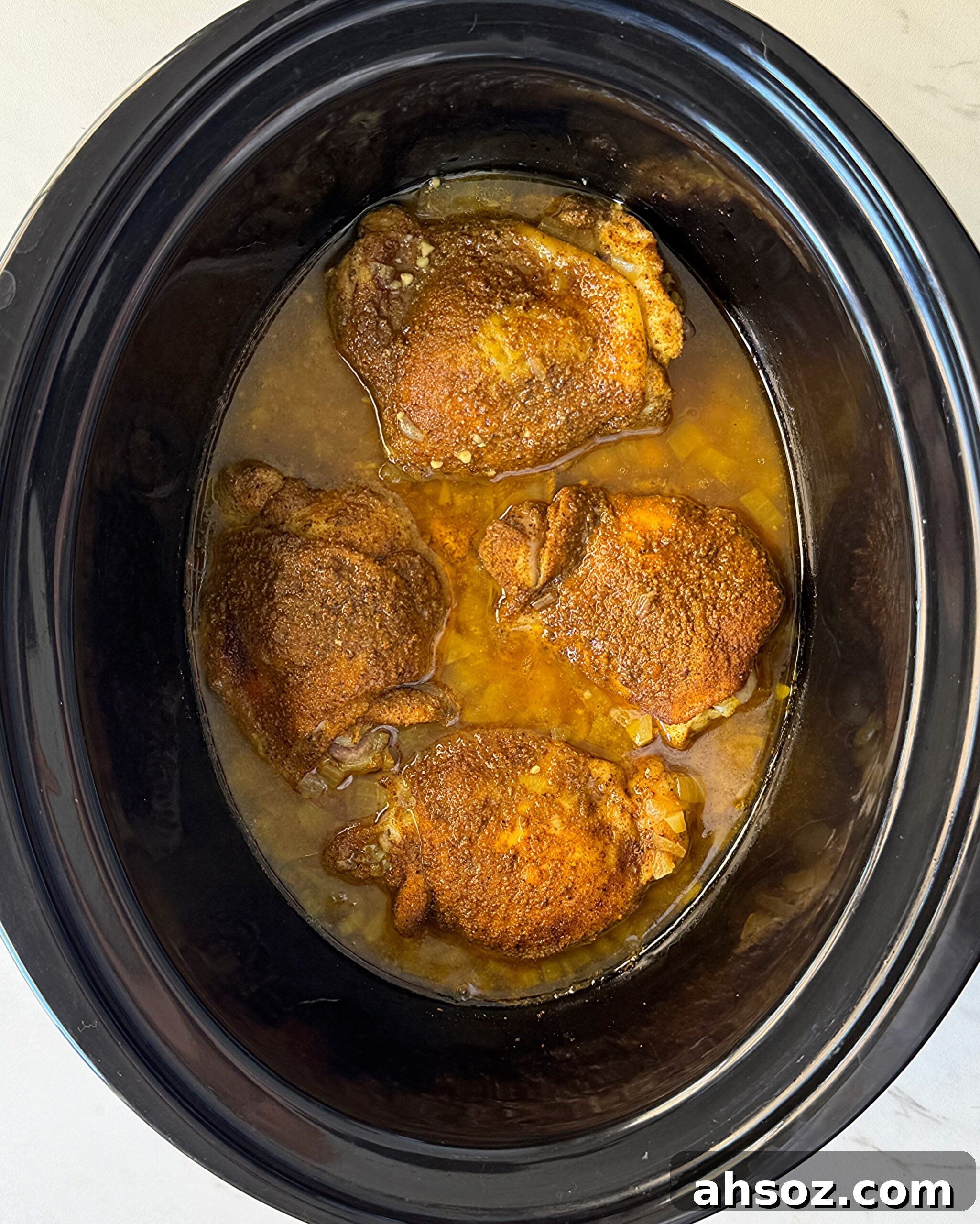 overhead shot of cooked North African chicken in a black slow cooker
